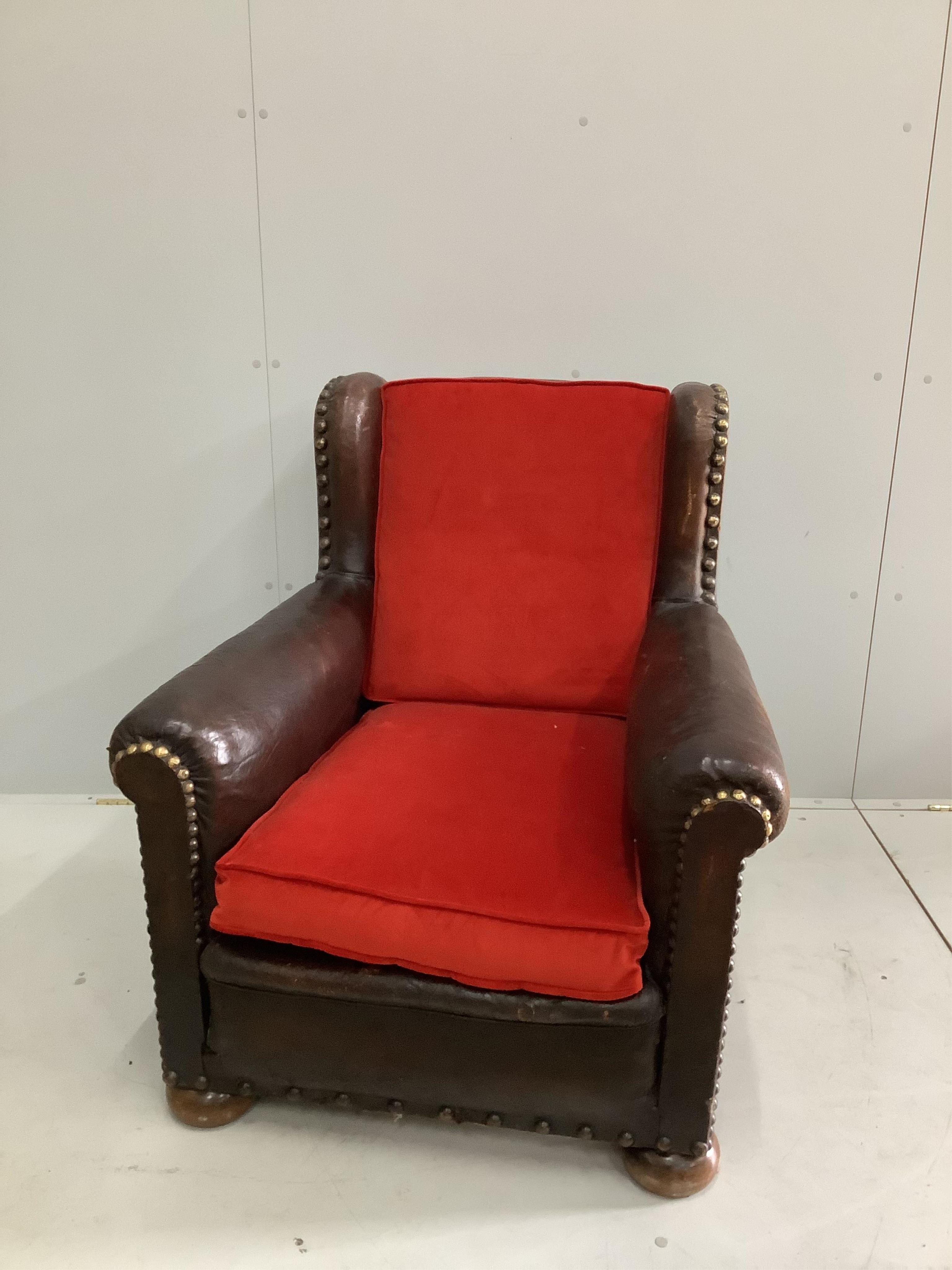 An early 20th century studded tan leather club armchair, width 84cm, depth 90cm, height 92cm. Condition - fair